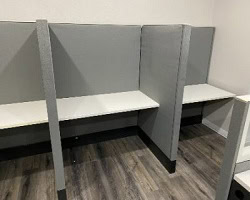 Call center workstations with privacy panels and white desks.