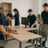 Team assembling ergonomic office furniture in a bright, modern workspace.