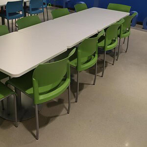 Steelcase white lunch table with green chairs for office or cafeteria use.