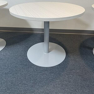 Modern round meeting table with Steelcase blonde wood finish and sturdy central support.