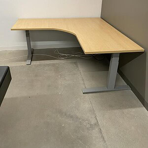 Shaped maple desk with electric height control, perfect for ergonomic workspace setup.