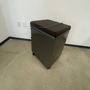 Mobile pedestal with cushion for office storage and comfort.