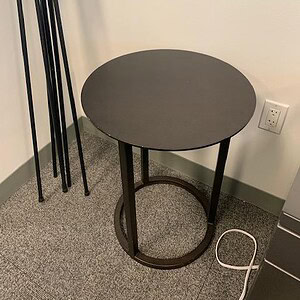 Black metal round occasional table by Keilhauer in modern office setting.