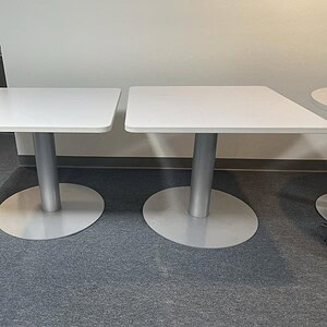 Modern 3-foot square white table with sturdy steel base for office or conference room.