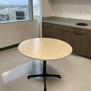 Modern 3-foot round maple table with black metal base, ideal for office or conference room settings.