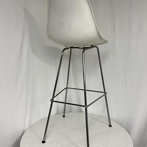 Herman Miller Eames bar height stool with white molded plastic seat and metal legs, ideal for modern.