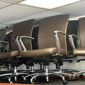 Brown leather office chairs with chrome bases for professional workspace comfort.