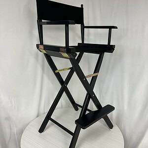 Foldable black director's chair with footrest, ideal for film sets, theaters, and outdoor events.