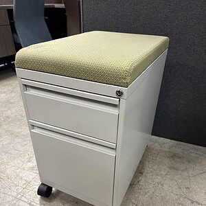 Mobile pedestal with green cushioned top for office organization and storage.