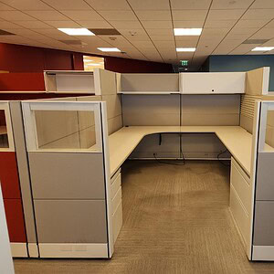 Modern grey glass office cubicle with high panels and workspace.