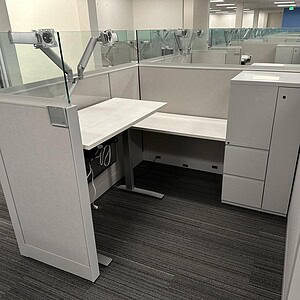 Height-adjustable Knoll Dividend desk in a modern office cubicle.