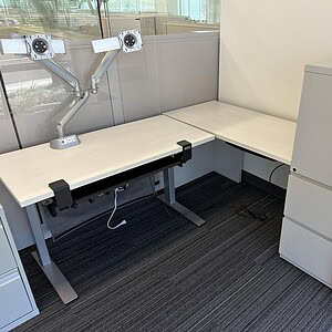 Height adjustable L-shaped desk for ergonomic workspace comfort. Modern design with clean lines, per.