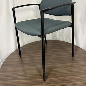 Grey stacking chair with black metal frame, ideal for office or conference rooms. Durable, stylish,.