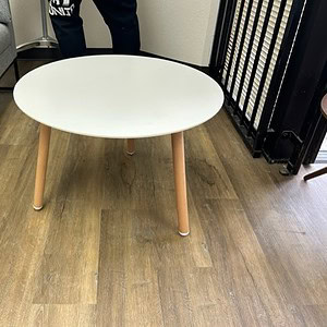 White round coffee table with wooden legs, perfect for modern living rooms and office spaces.