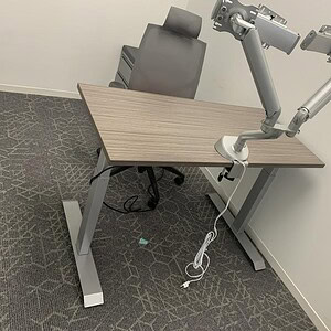 Adjustable height desk with robotic arms, ideal for ergonomic workspaces and tech setups.