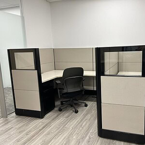 Office cubicle with dark tone panels and glass accents, ideal for modern workspace privacy.