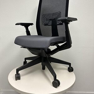 Modern Haworth office chair with grey fabric and black mesh backrest, adjustable armrests, on white.