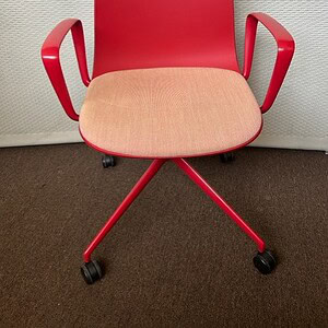 Conference chair with vibrant red iridescent finish, ergonomic design, and caster wheels for office.