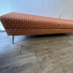 Ottoman with orange and white geometric fabric, 6-foot length, modern design.