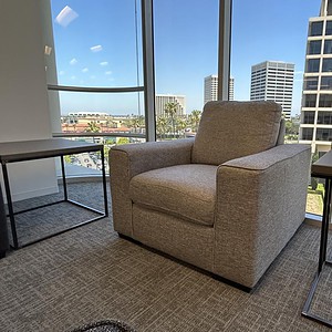 Neutral-colored lounge chair in modern office with city view.