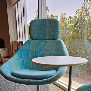 Blue contemporary lounge chair with attached side table for office or home use.