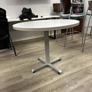 Round white table with steel legs, ideal for office or conference room settings.