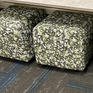 Green patterned ottoman seats with casters for versatile office or lounge use.