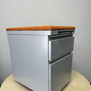 Herman Miller orange cushion mobile pedestal on casters, ideal for office storage and organization.