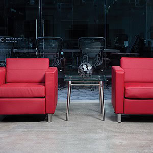 Pair of modern red fabric armchairs with metal legs in a contemporary office setting.