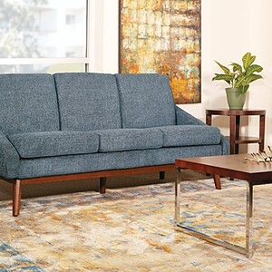 Century modern sofa with blue upholstery and wooden legs. Perfect for stylish living room decor.