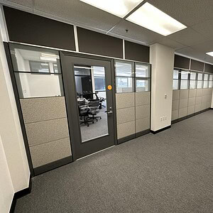 Modern Herman Miller Ethospace office partition with glass door and beige panels.