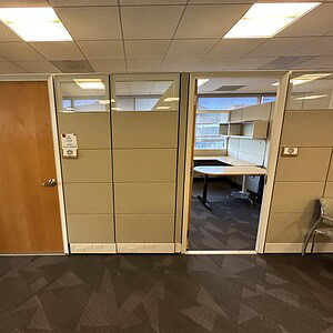 Office cubicles with glass partitions in a modern workspace.