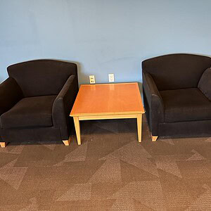 Herman Miller black suede lounge chairs with a small wooden table in between, modern office or loung.