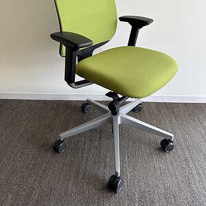 Office chair with lime green mesh back and black armrests, adjustable height, and ergonomic design.
