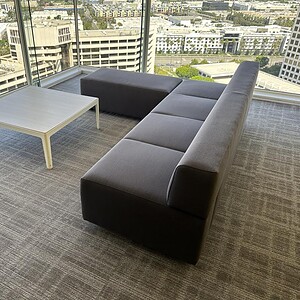 Coalesse Circa Charcoal 7ft sofa with matching ottoman in a modern office setting.