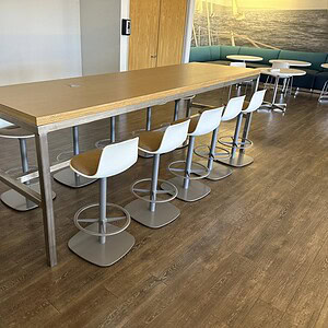 Modern conference table with wood top and steel base for collaborative workspaces.