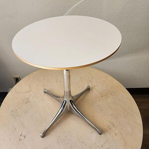 Herman Miller Nelson pedestal side table with a round white top and chrome base.
