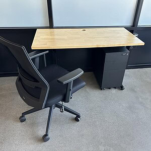 Office desk with black base and maple wood top for modern workspace.