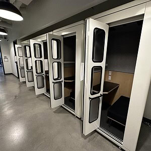 Privacy phone booths with acoustic insulation for quiet work environments.