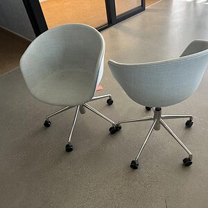Grey bucket-style office chairs with pneumatic height adjustment on casters, modern design.