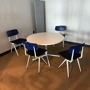 Blue Barcelona chair around a white round table in a contemporary office setting.