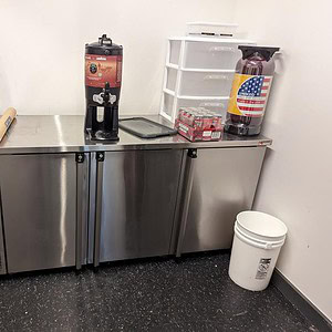 Commercial beverage dispenser setup with stainless steel counter and supplies.