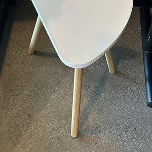 Modern white triangle-shaped kidney table with natural wood legs for stylish interior decor.