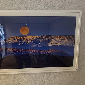 Orange moon over snow-capped mountains at dusk, creating a striking landscape scene.