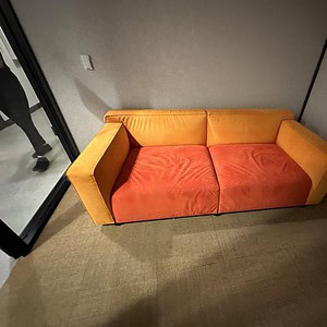 Modern orange suede couch in a minimalistic room setting.