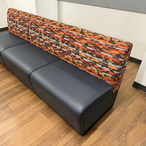 Modern banquet seating with a colorful sunset wave patterned backrest and dark gray base.