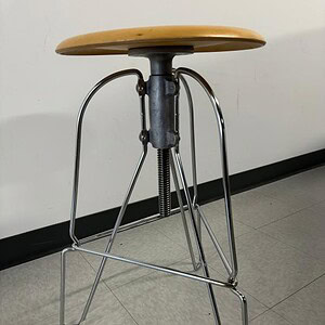 Modern Jeff Covey stool with wooden seat and wire metal legs, stylish and functional.
