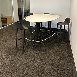 Herman Miller Exclave bar height table with four black chairs in modern office setting.