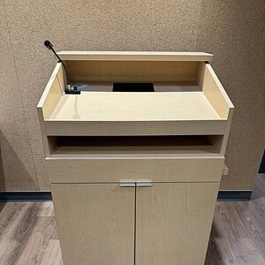 Portable maple podium on casters with built-in storage compartment.