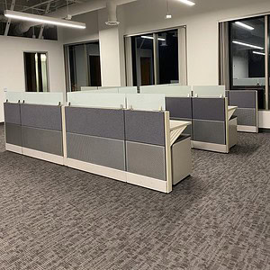 Modern office cubicles with glass panels and Herman Miller design.